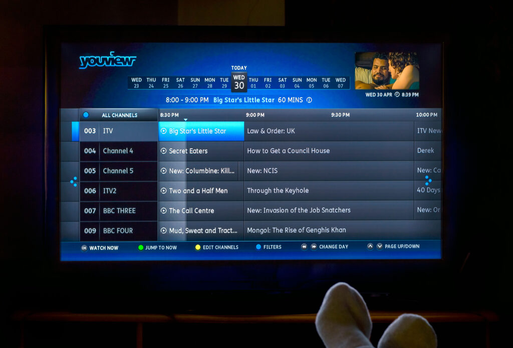 Picture of someone's feet up watching TV via YouView platform to highlight importance of consistent metadata in TV viewing experience.